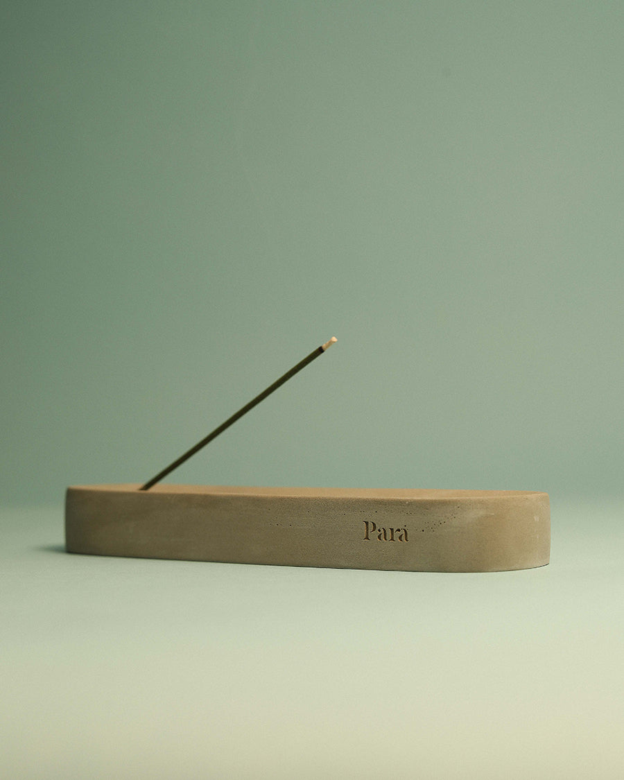 Raw texture and tone variations on a handmade concrete incense stand Incense holder with a single incense stick on a light green background