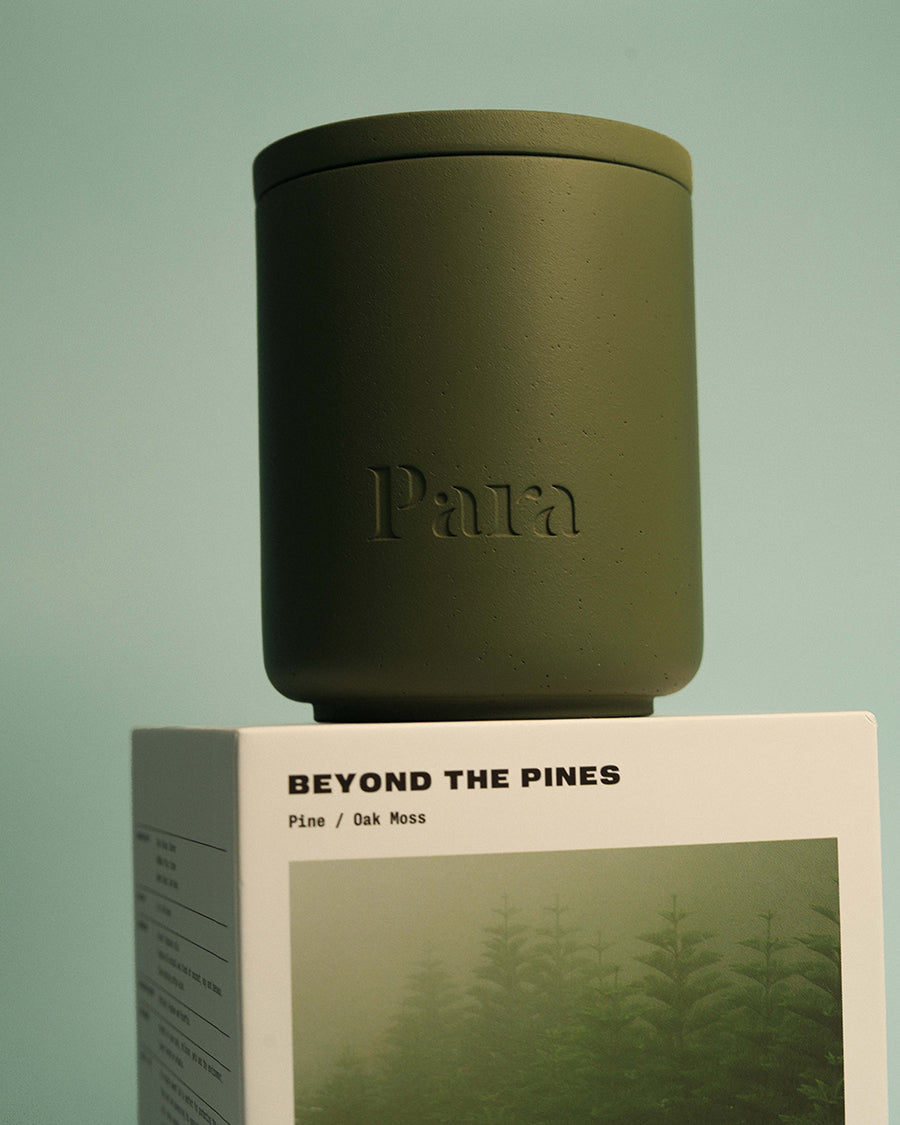 Minimalist green cement candle jar with lid featuring pine and balsam home fragrance Green candle with 'Para' branding on a box labeled 'Beyond the Pines' against a green background