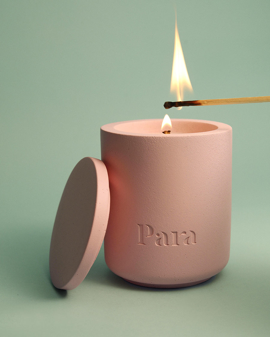 Pink candle with 'Para' branding being lit against a light green background