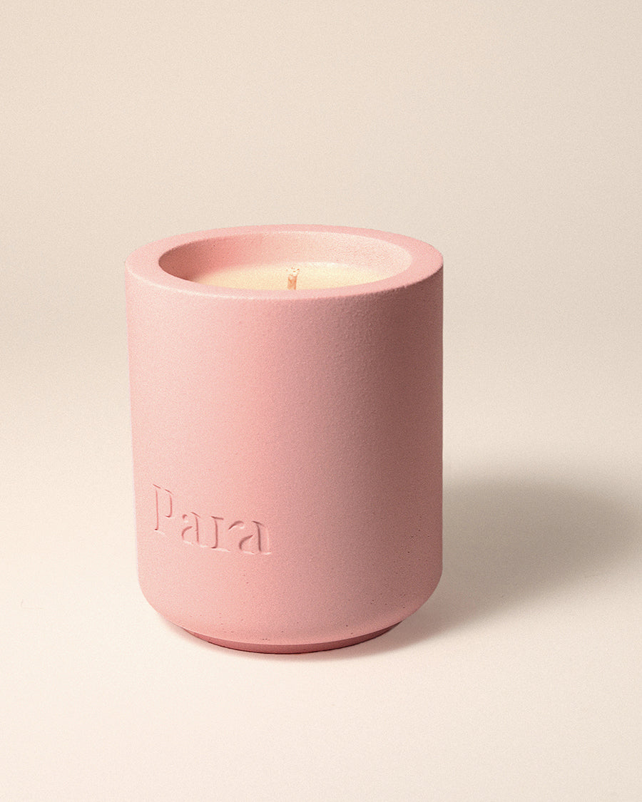 Pink candle in a textured concrete container with 'Para' branding on a light beige background